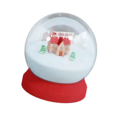 Ziemassvētku uzlīme māja un sniegs stikla bumbā ar sarkanu pamatni